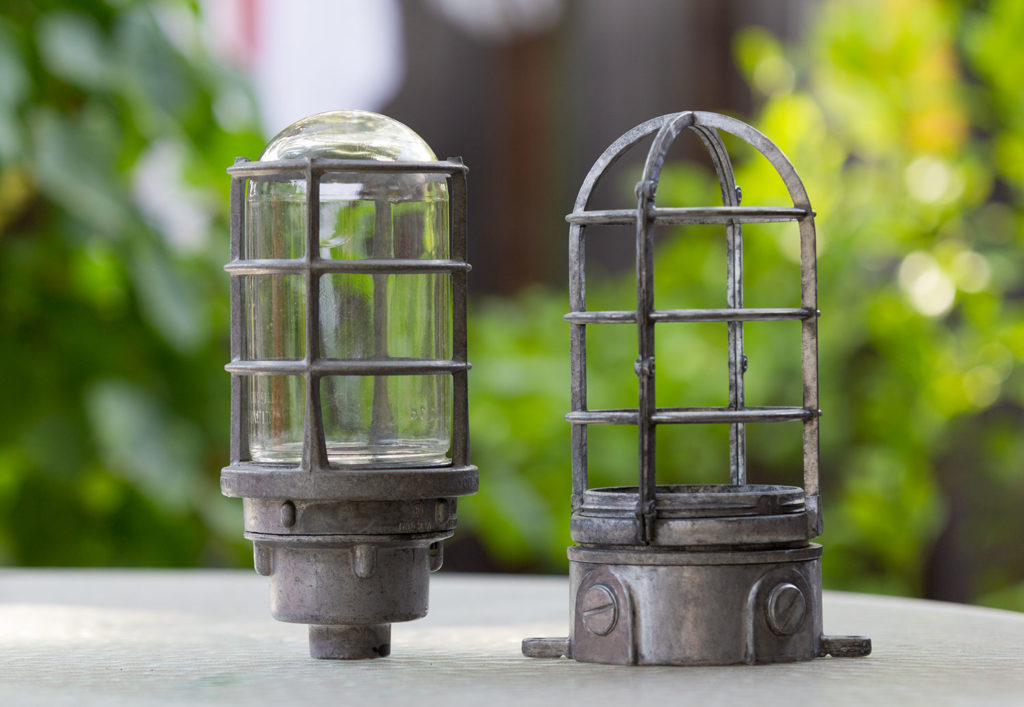 two outdoor light fixtures standing on a table