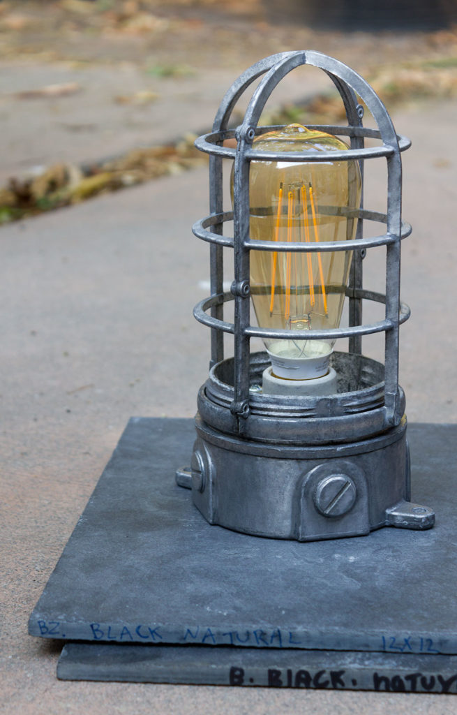 repurposed outdoor light fixture with LED filament bulb on two black slate tiles