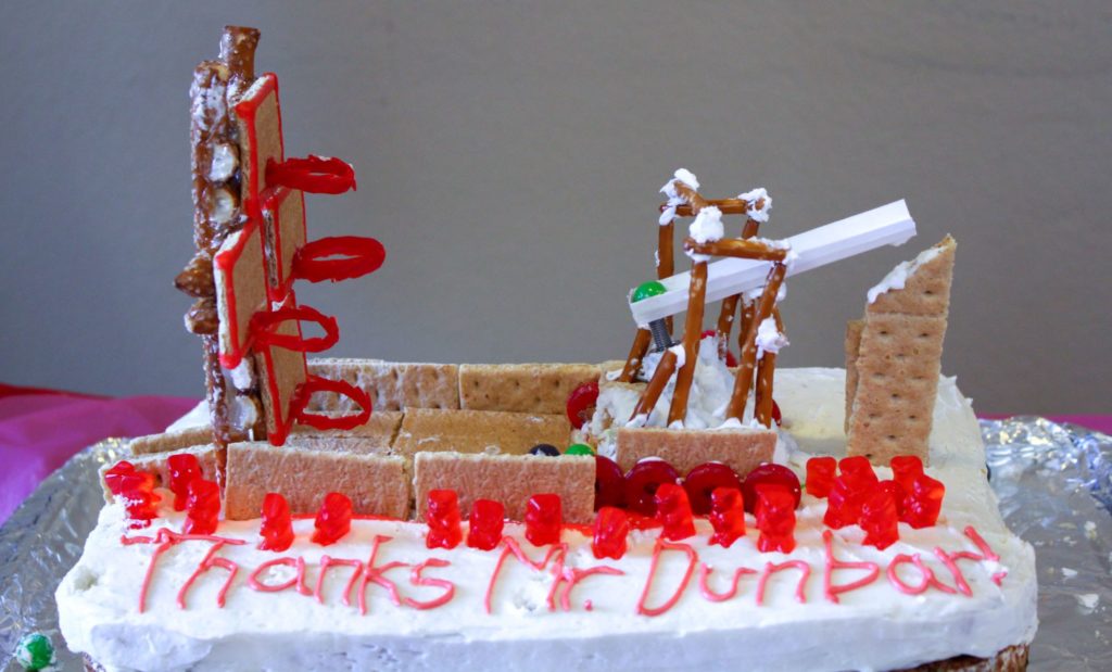 a sheet cake topped with a model of a robot playing basketball made out of pretzel sticks and candy