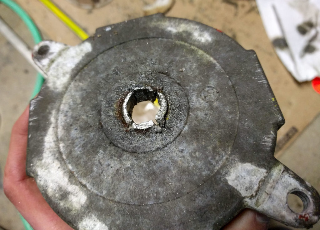 hacksawing a rusty pipe out of a metal light fixture