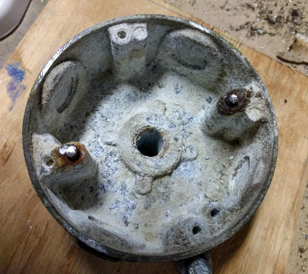 inside of a light fixture, covered with corrosion and rust