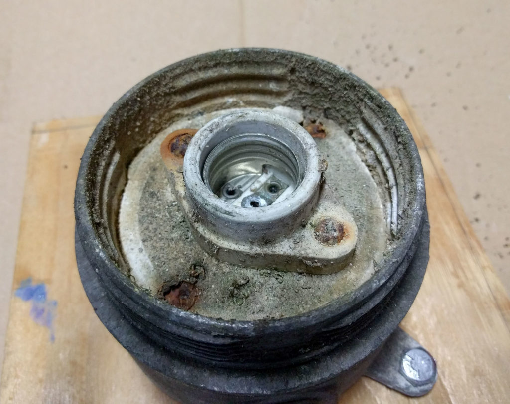inside of a light fixture, covered with corrosion and rust