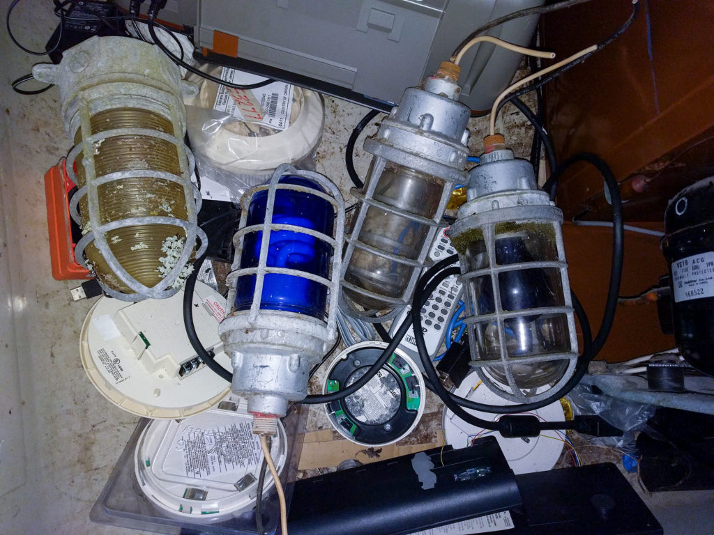four outdoor light fixtures in a pile of E-waste