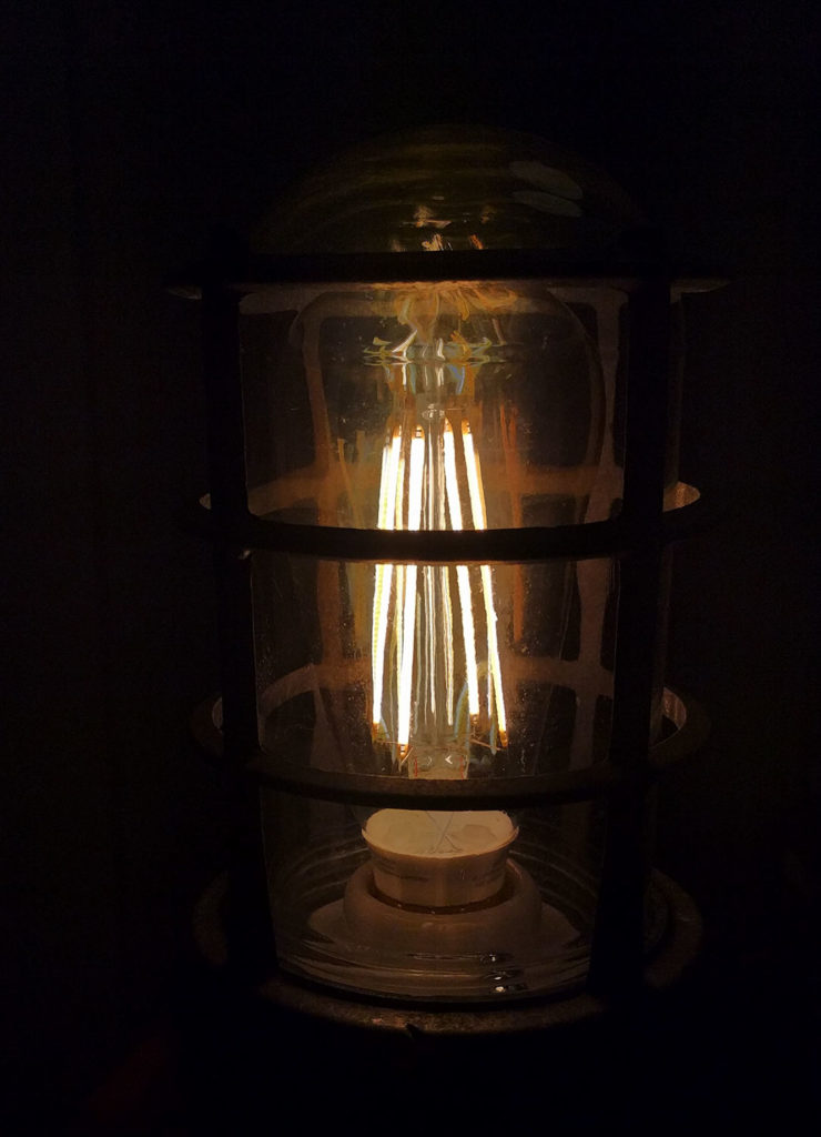 glowing LED filament light bulb inside a re-purposed outdoor light fixture