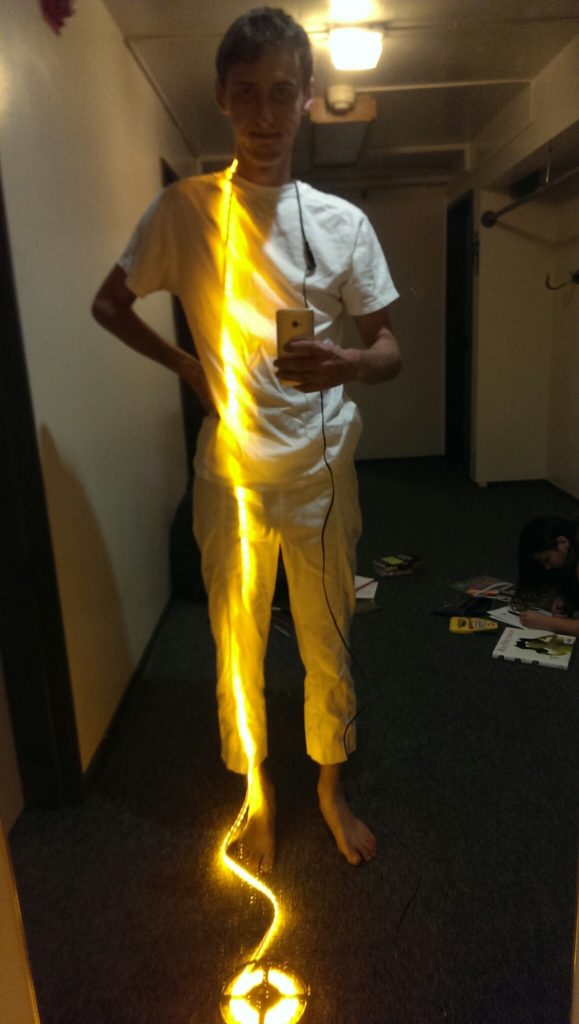 person standing with an amber LED strip visible under clothing